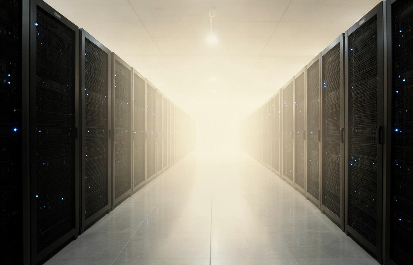 Corridor of dark server racks with small blue indicator lights, representing cloud hosting infrastructure